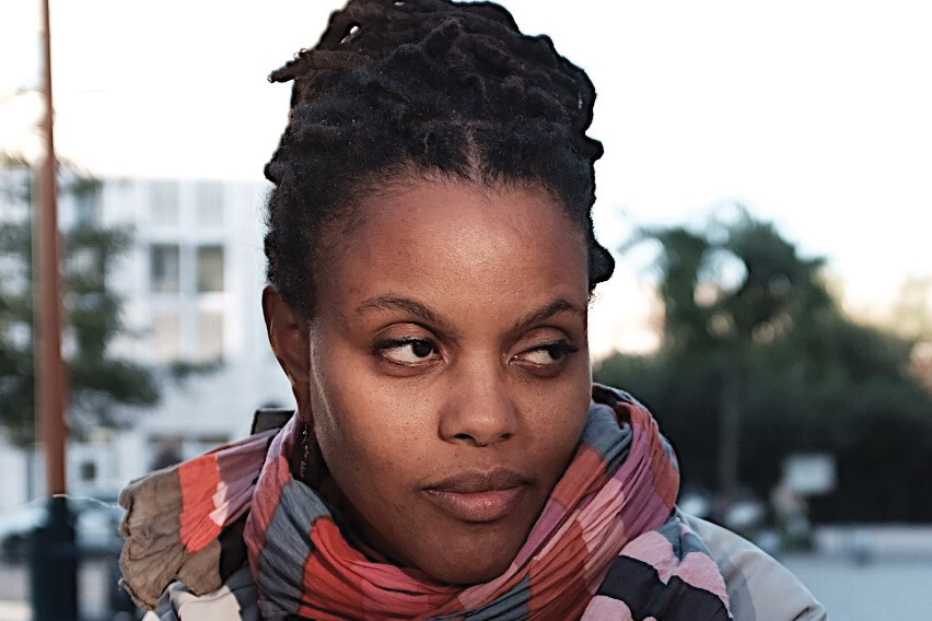 A headshot of a women wearing a colorful scarf looking to the side