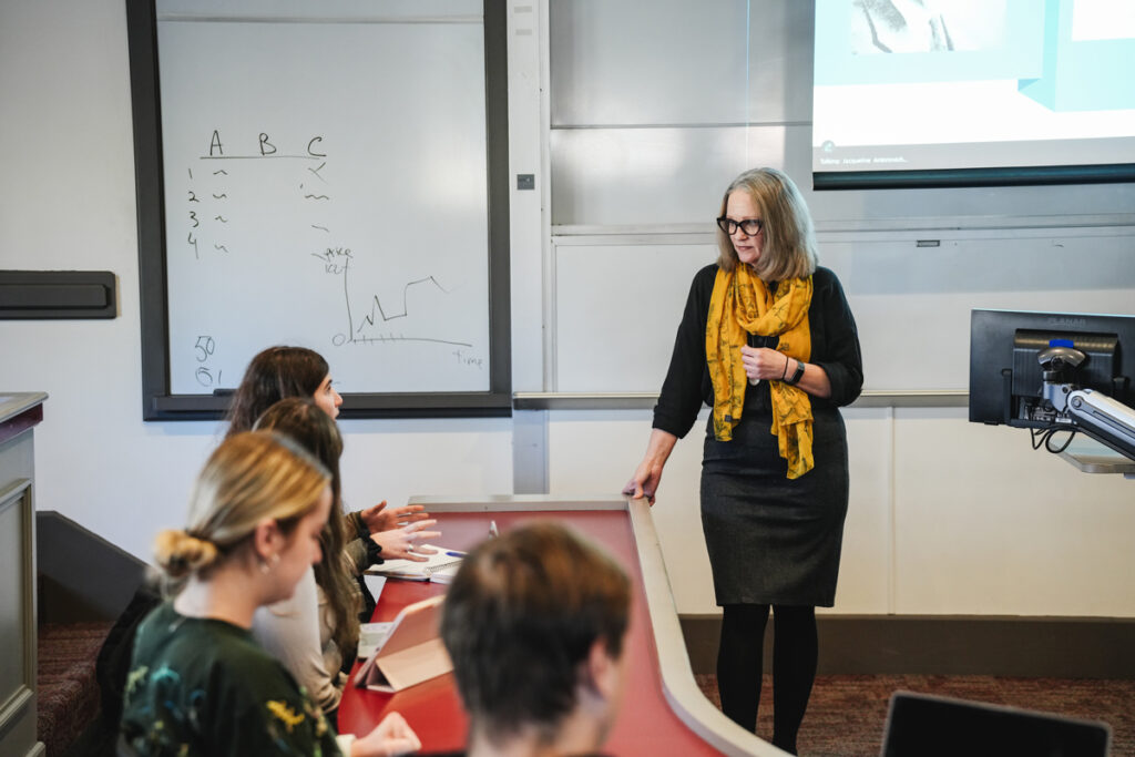 A Muhlenberg faculty member listens to a student speaking in a classroom.