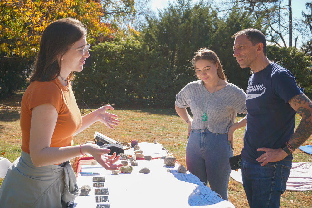 Indigenous Initiatives A Muhlenberg student stands behind a table to explain a the Hitekw Project during an autumn day.