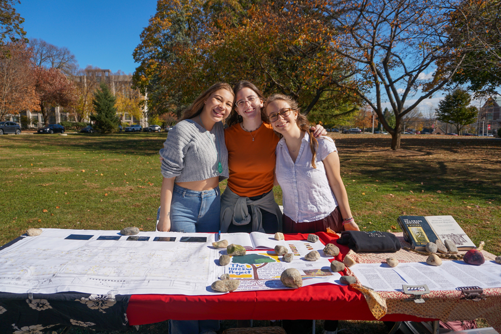 Indigenous Initiatives A trio of Muhlenberg students pose in front of a table with information about the Hitekw Project on campus during the fall.