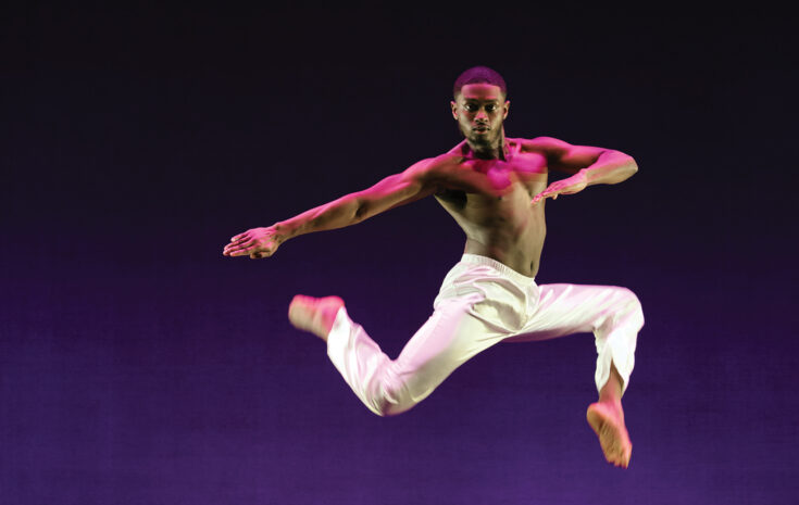 A college student dancer leaps across the stage during a performance