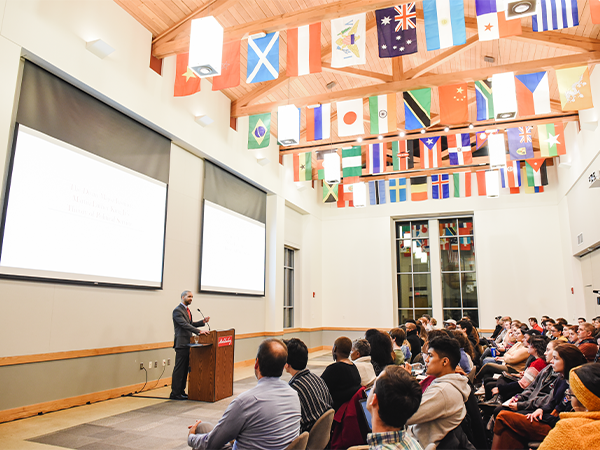 students listen to lecture beneath many flags