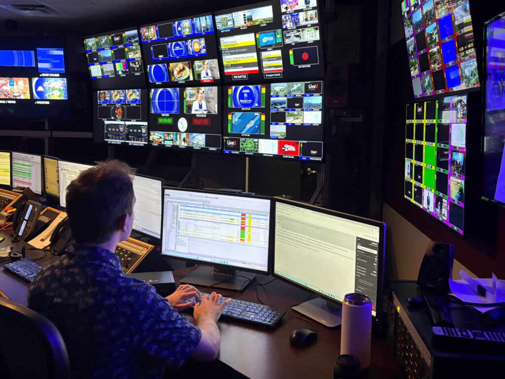 student looks at many screens in media studio