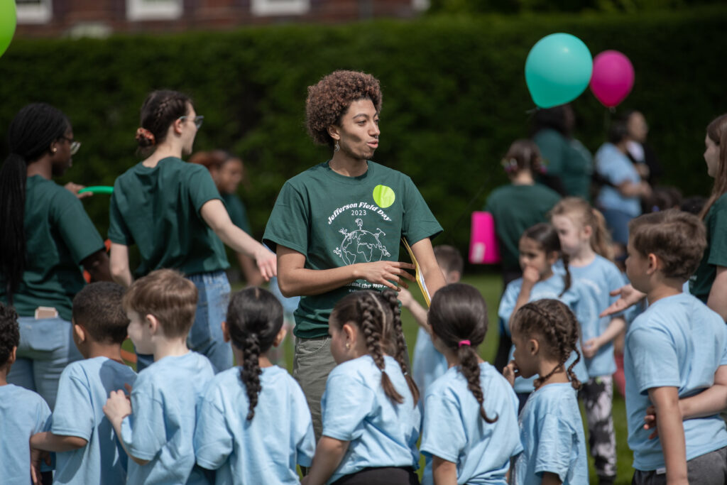 A college student stands in front of a group of elementary school students