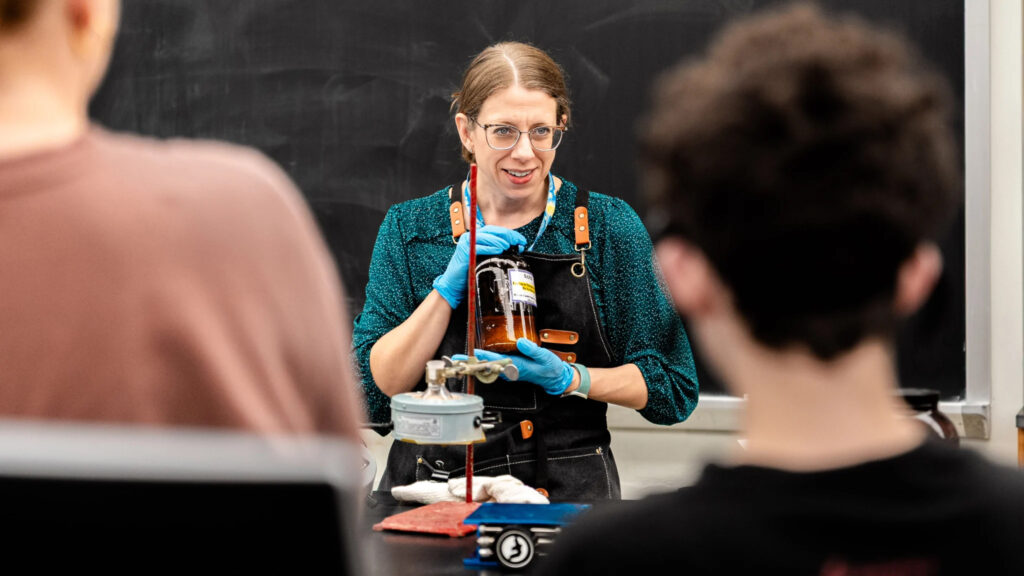 Muhlenberg faculty, Keri Colabory, holds equipment in a lab while speaking to students.