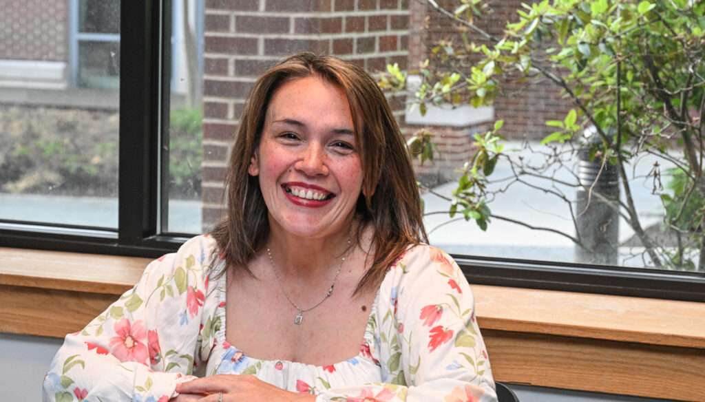 A Muhlenberg graduate student smiles while seated at a table.