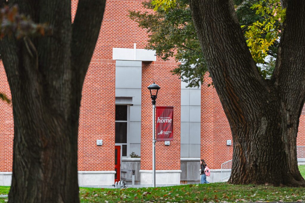 A red banner that says Welcome Home hangs from a light post between two trees