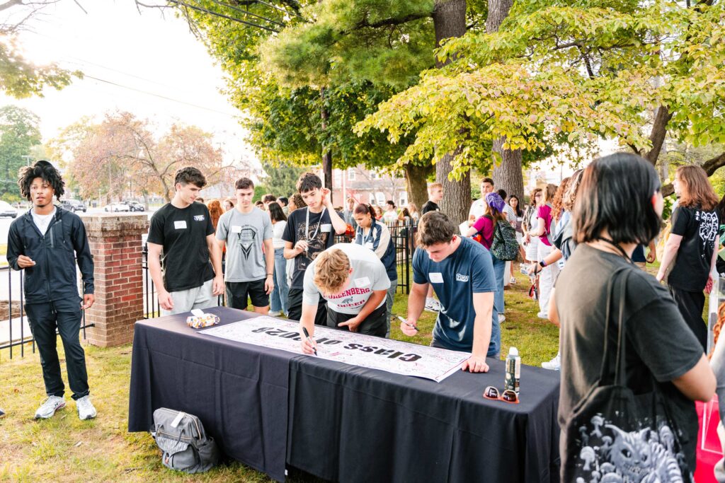 Two college students sign a banner that says Class of 2028