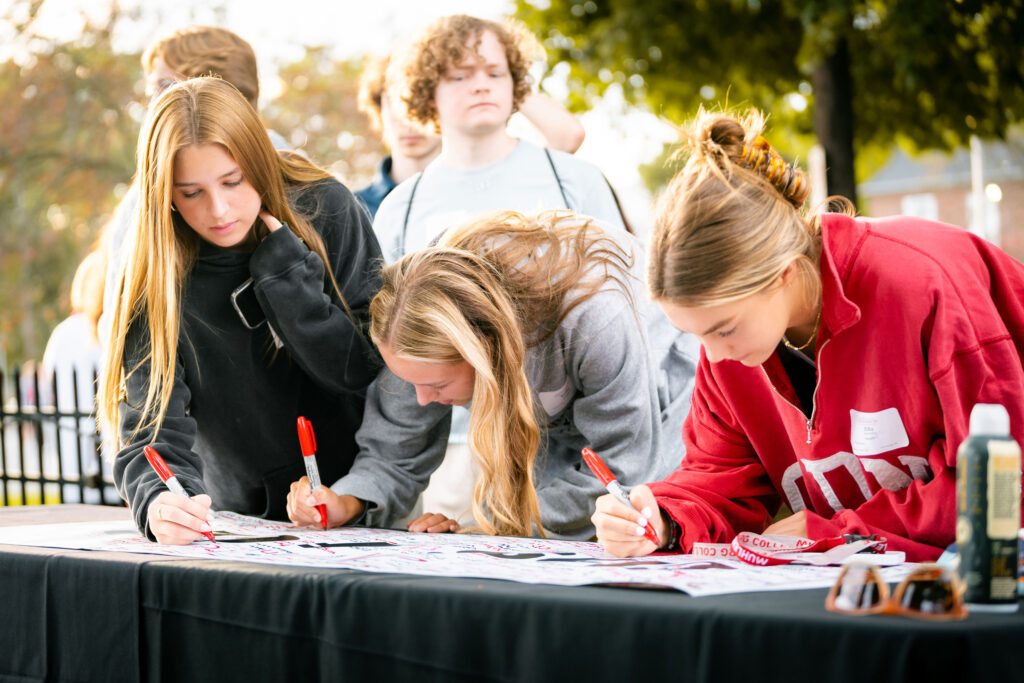 Three college students sign a paper that says Class of 2028