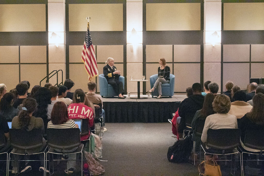 Admiral Levine sits on stage in front of a large crowd.