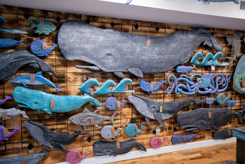 About a dozen carved whales on a wall