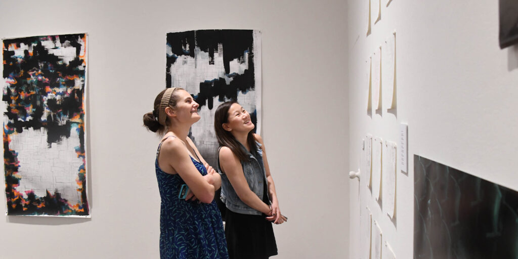 Students examine paintings on the wall of the Martin Art Gallery.