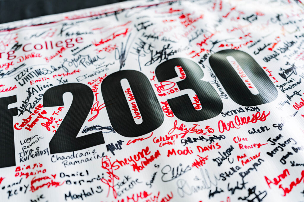 A banner that says 2030 with red and black signatures on it