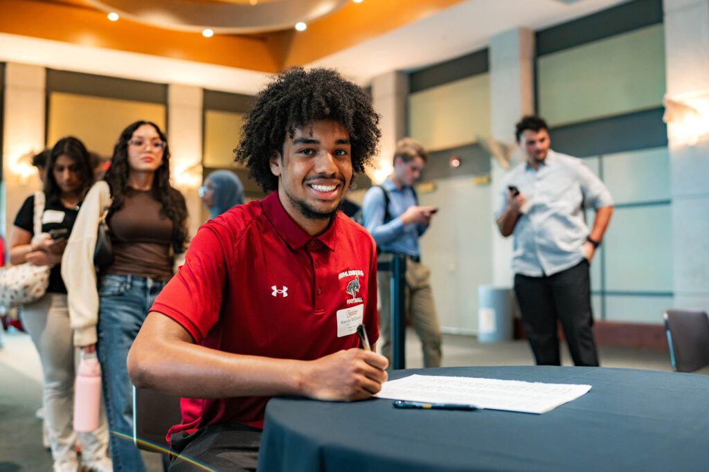 A Muhlenberg College student with curly dark hair signs the matriculation ledger