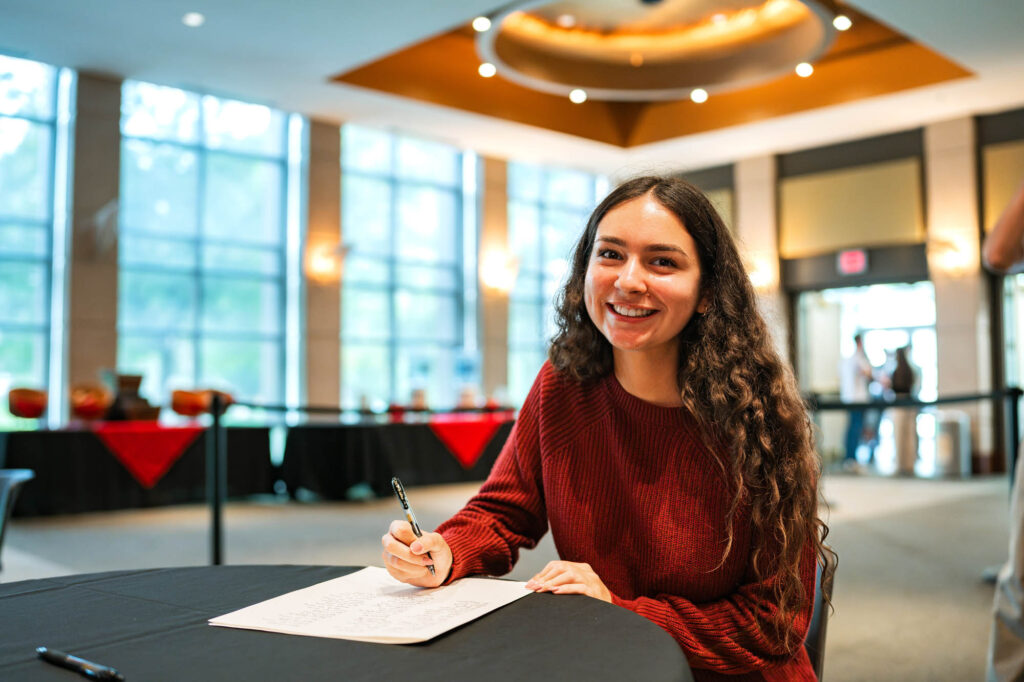 A Muhlenberg College student with long dark hair signs the matriculation ledger
