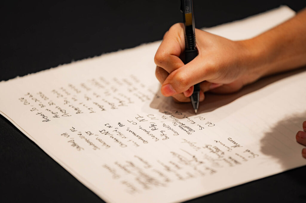 A close-up of a hand signing the Muhlenberg College matriculation ledger