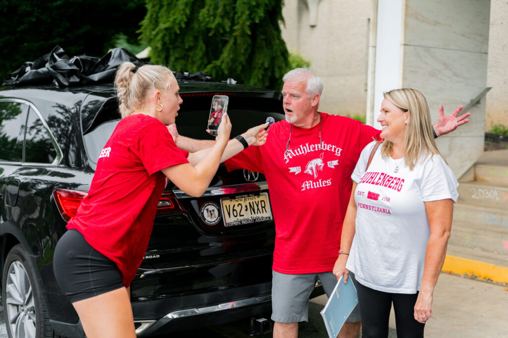 A Muhlenberg College student takes a photo of two Muhlenberg College parents during move-in