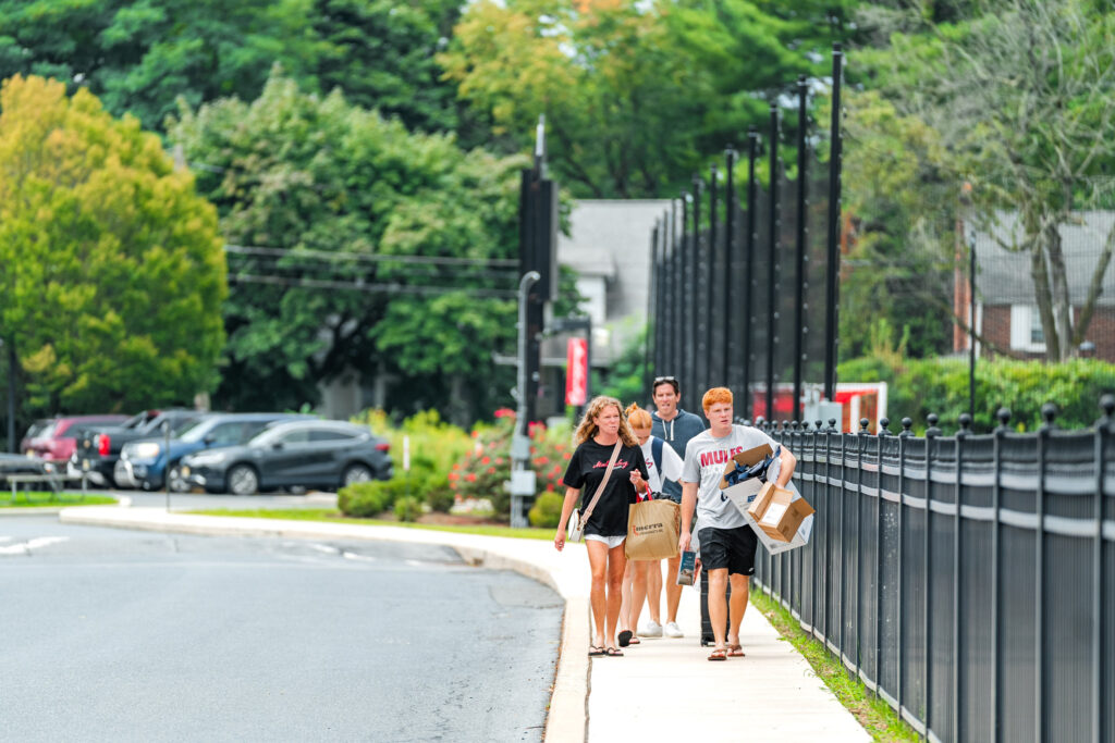 A family carries belongings down the sidewalk during move-in at Muhlenberg College