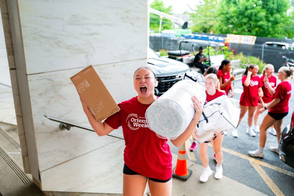 A Muhlenberg College student yells while carrying belongings during move-in