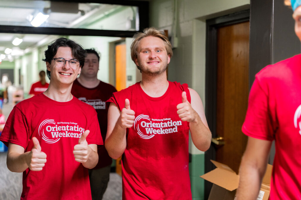 Two Muhlenberg College students in red shirts give thumbs ups during move-in