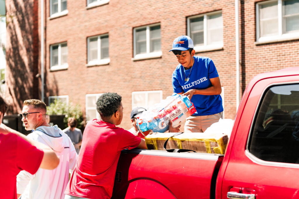 A college student hands a pallet of Gatorade to another student from the bed of a truck during move-in