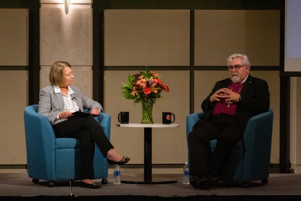 College President Kathleen Harring speaks with Rev. Guy Erwin on stage.