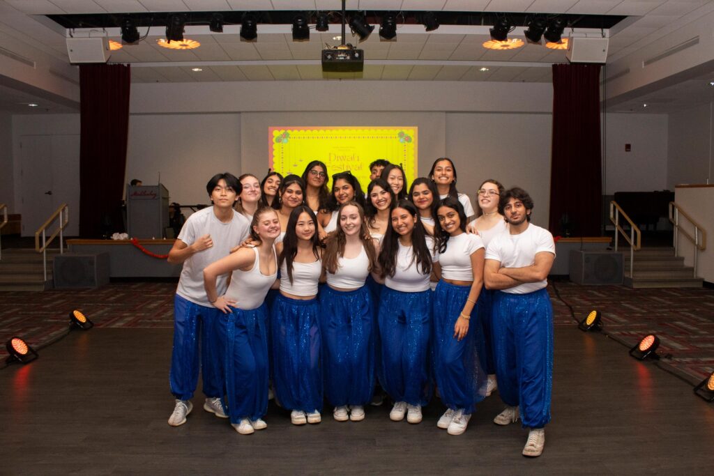 A group of college students wearing matching white T-shirts and sparkly blue pants