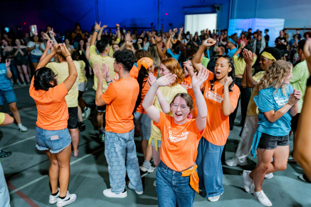 Welcome Weekend and Orientation A group of Muhlenberg College students in orange orientation T-shirts dance
