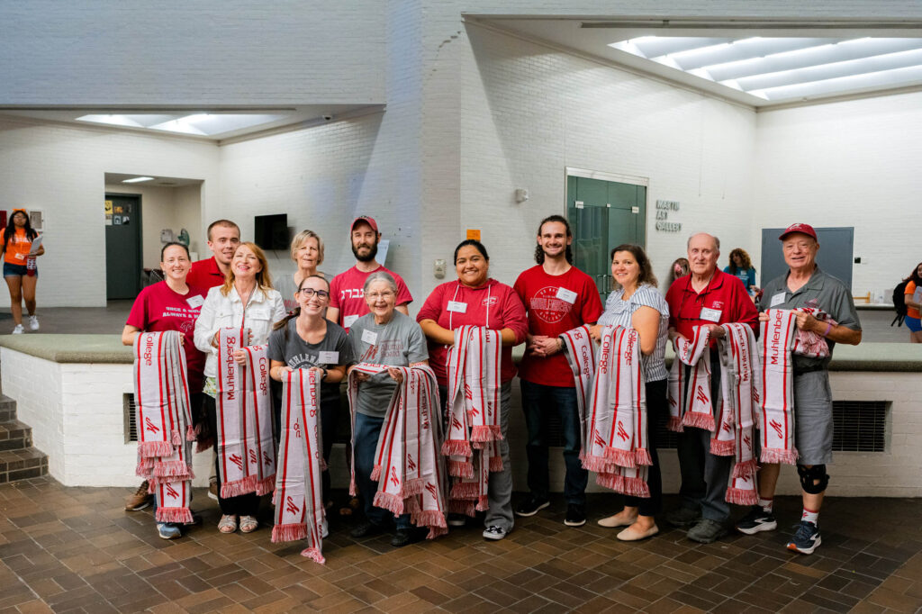 A group of Muhlenberg College alumni hold Muhlenberg College scarfs