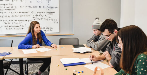 A group of students and a professor sitting at a table in a classroom.