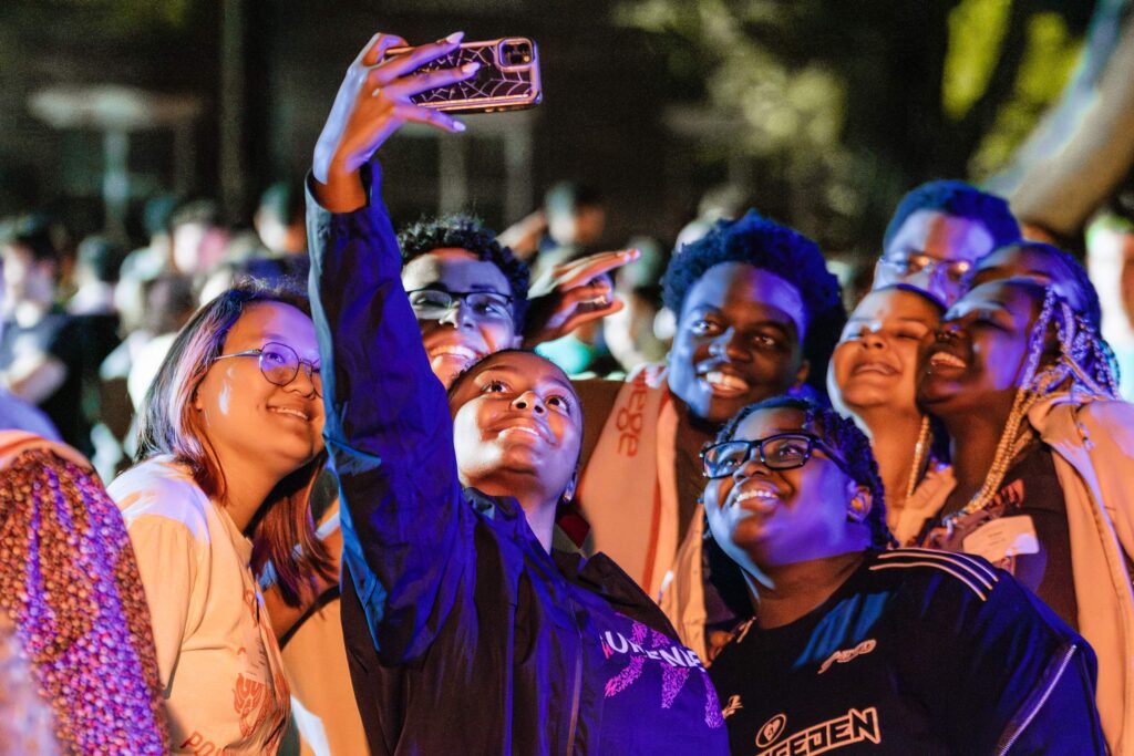 A group of college students poses for a selfie at night