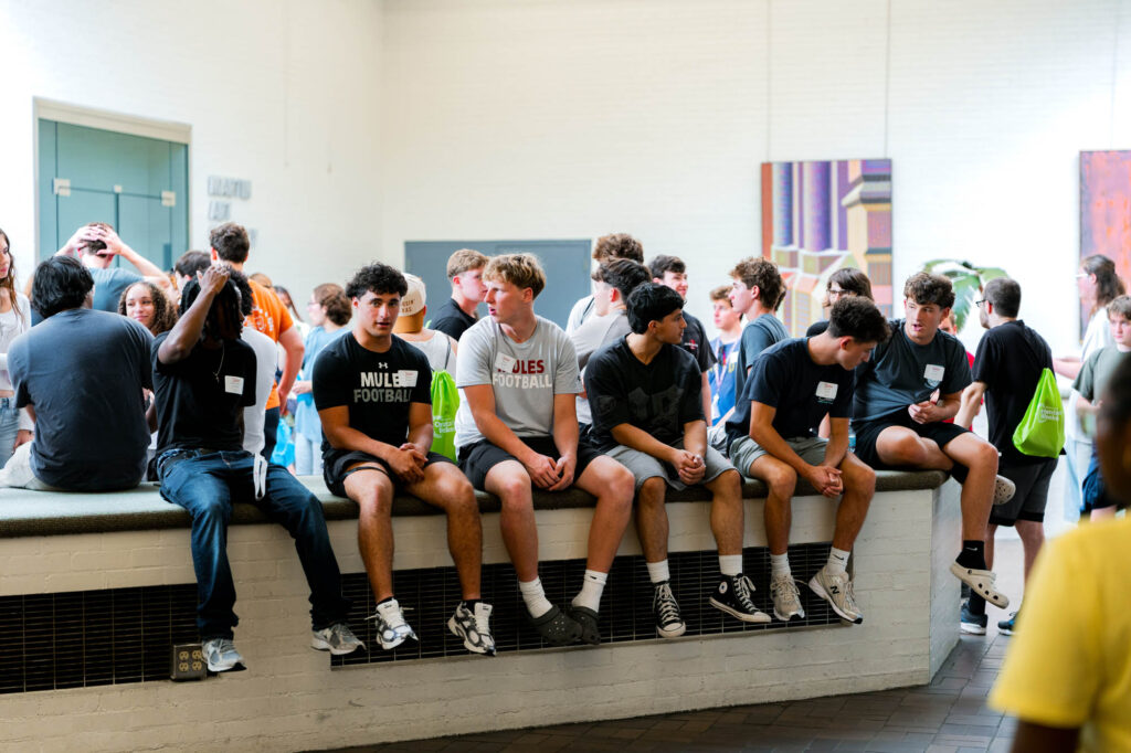 A group of new Muhlenberg College students sits on a ledge inside a building