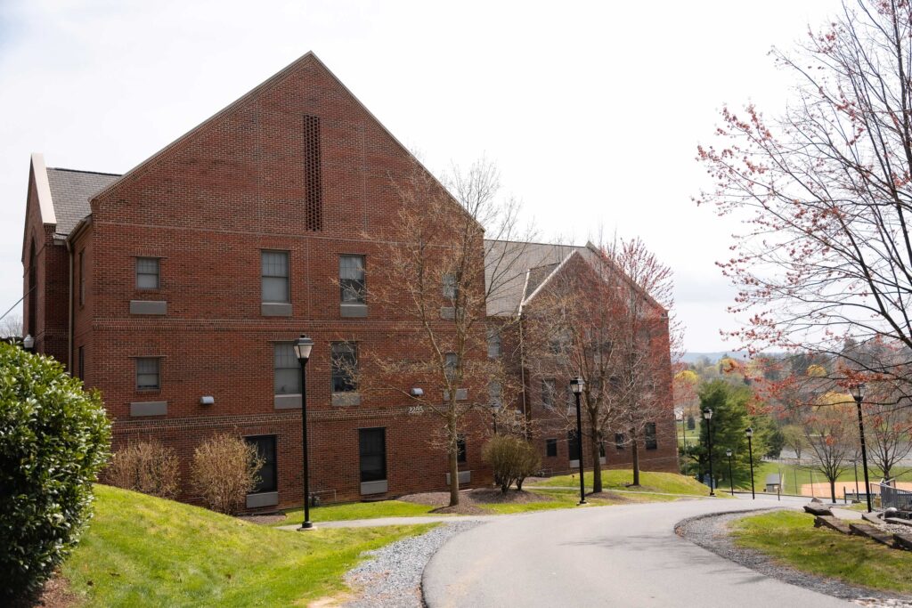 A brick college apartment building overlooking a park with a lake