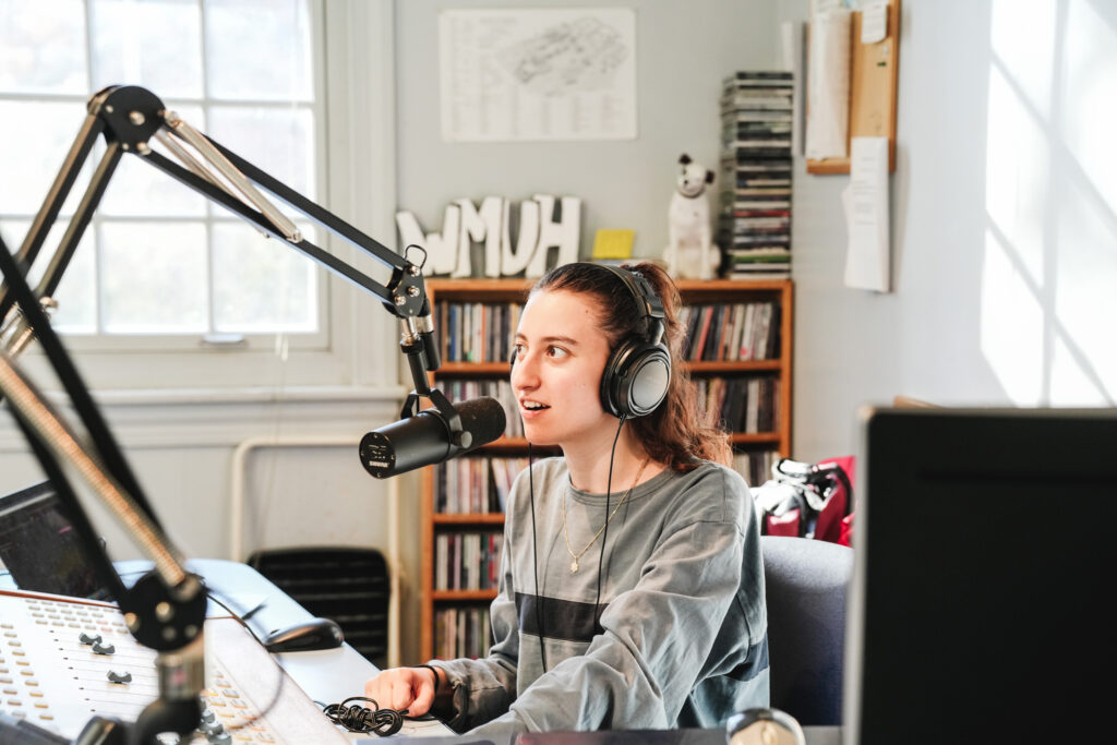 A college student wears headphones and speaks into a studio microphone