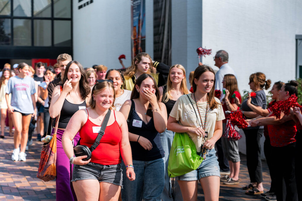 A group of new Muhlenberg College students walks through a group of cheering faculty and staff