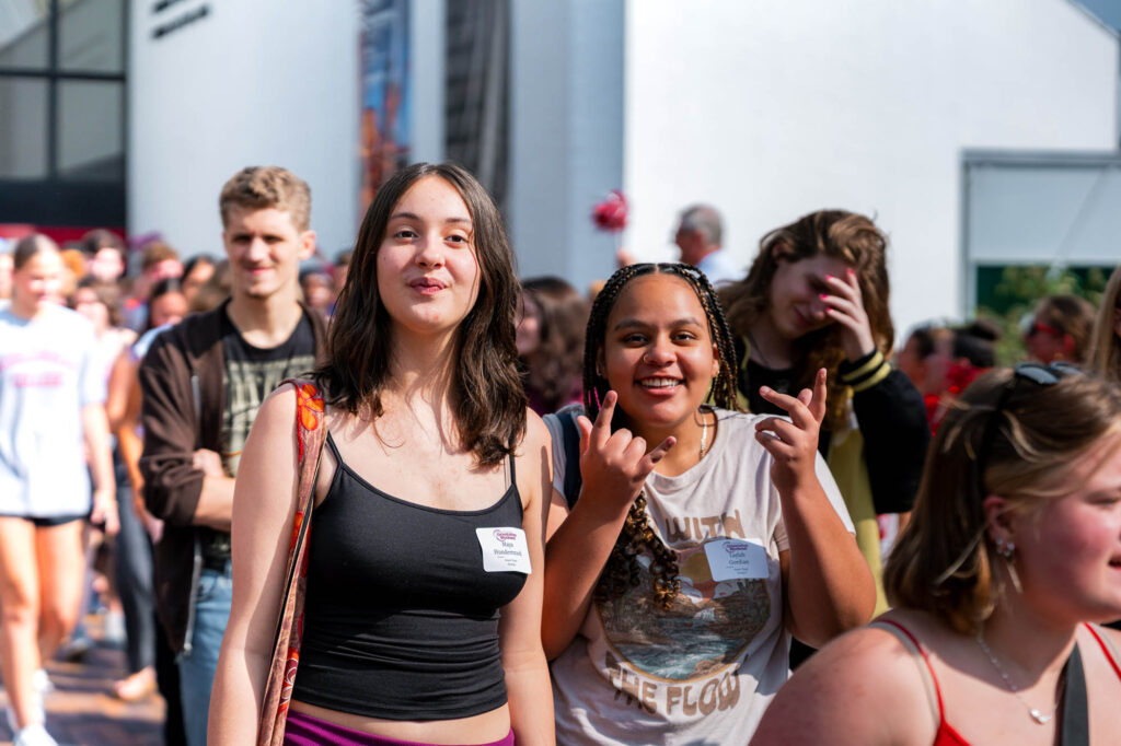 Two new Muhlenberg College students walk past cheering faculty and staff