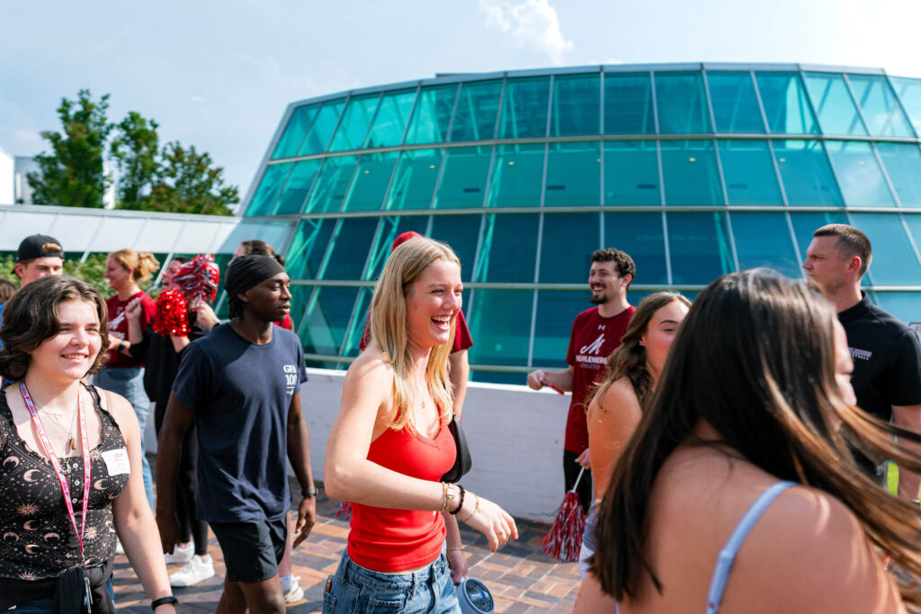 New Muhlenberg College students walk past a building made of windows