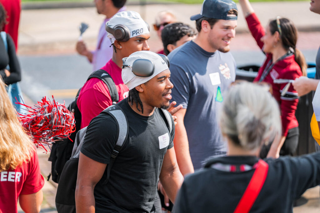 New Muhlenberg College students wearing headphones walk on campus during orientation