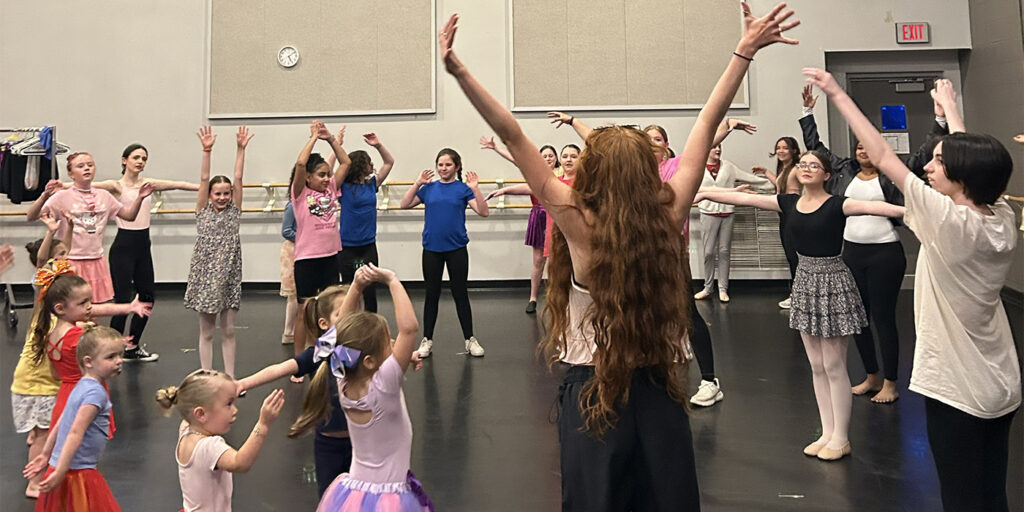 College students lead a group of young dancers in a dance class.