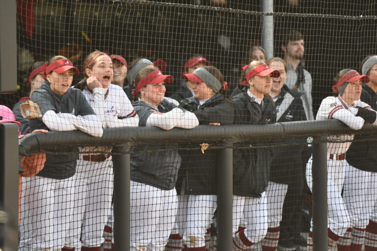Muhlenberg Mules softball players cheer from the dugout.